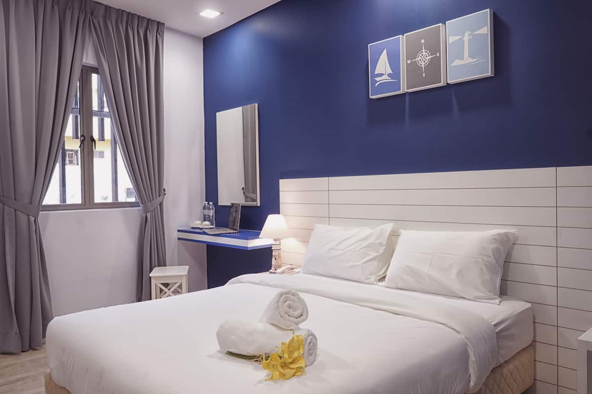 Una habitación de hotel con cama, escritorio, espejo y ventana con cortinas.