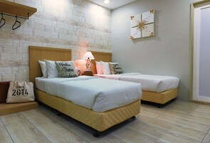 Un dormitorio con dos camas, cabeceros de madera, una mesita de noche con lámpara y un reloj de pared.