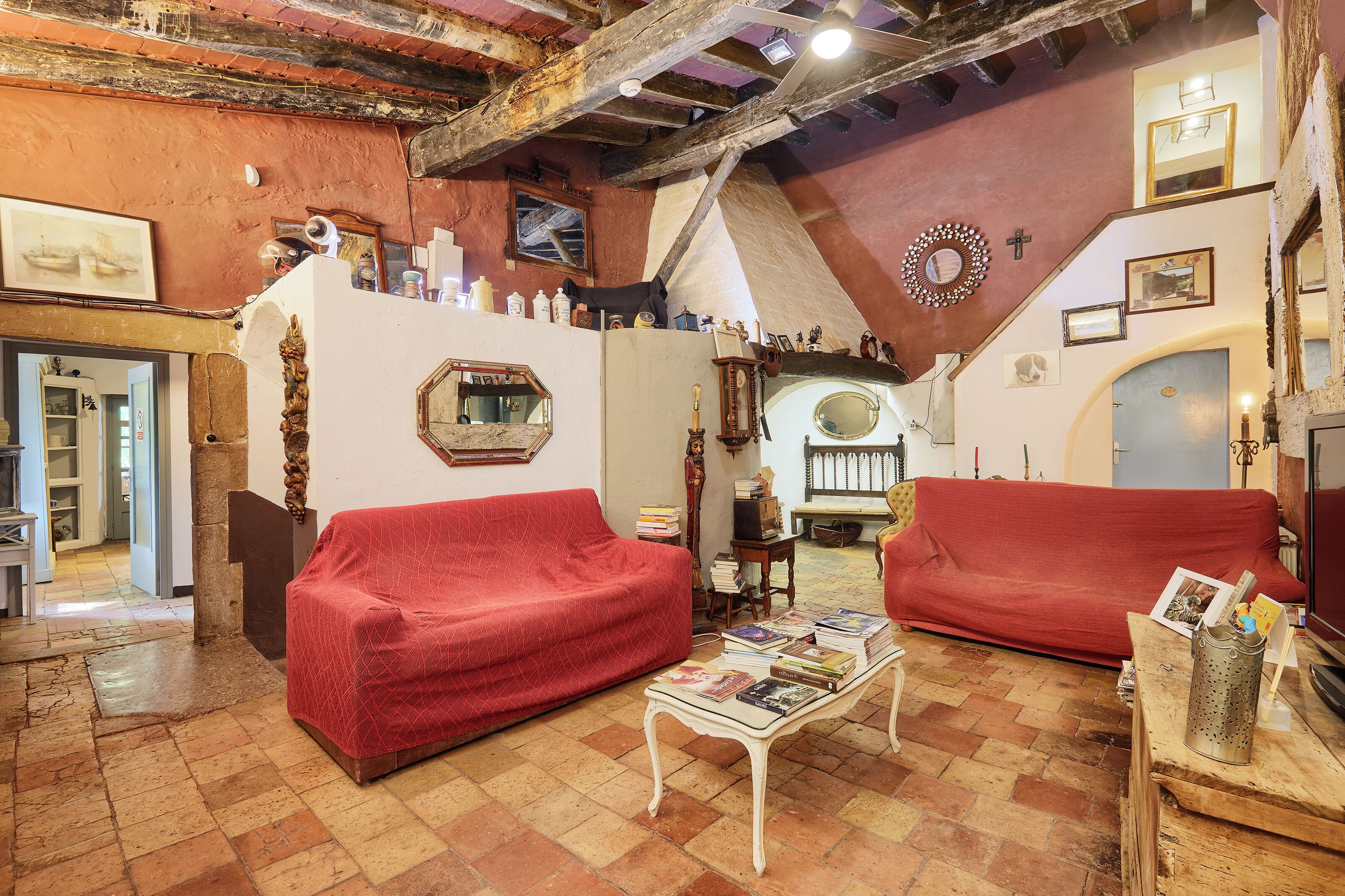 A cozy living room with red sofas, a coffee table with books, and a rustic ceiling.