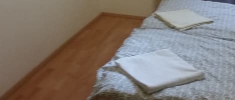Un dormitorio con cama, televisor de pantalla plana en la pared y ventana con cortinas.