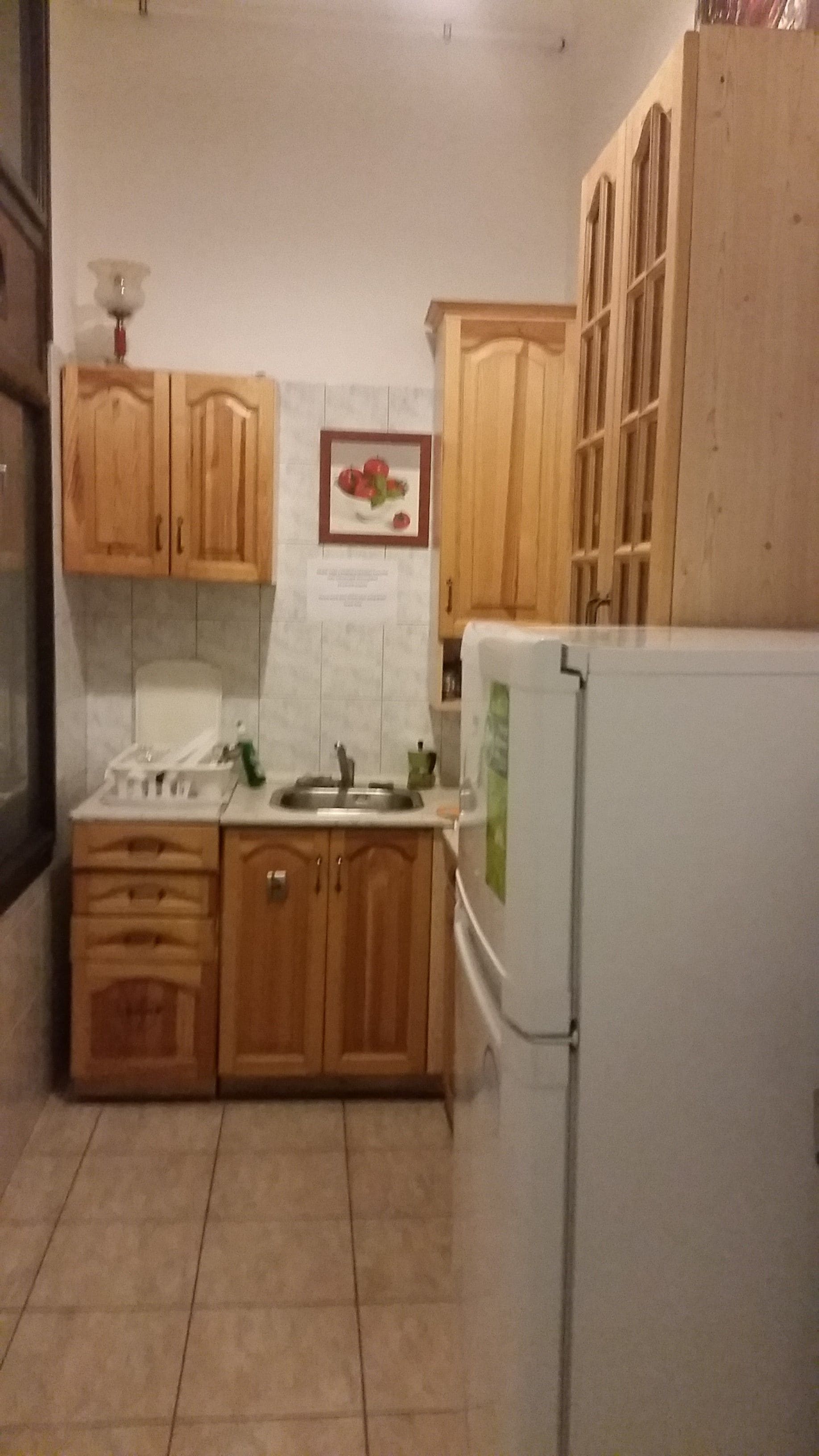 Una cocina con armarios de madera, un refrigerador blanco y un salpicadero de azulejos.
