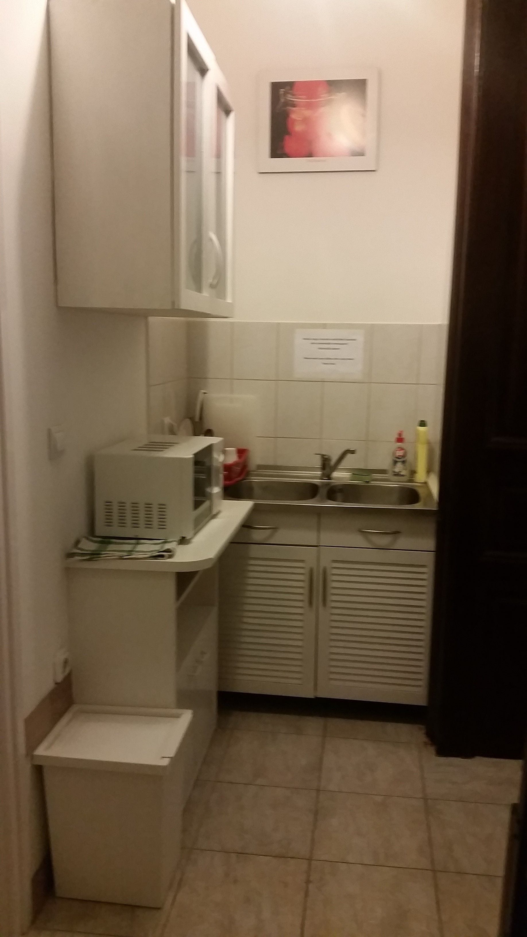 Una cocina pequeña con microondas, fregadero y armarios.