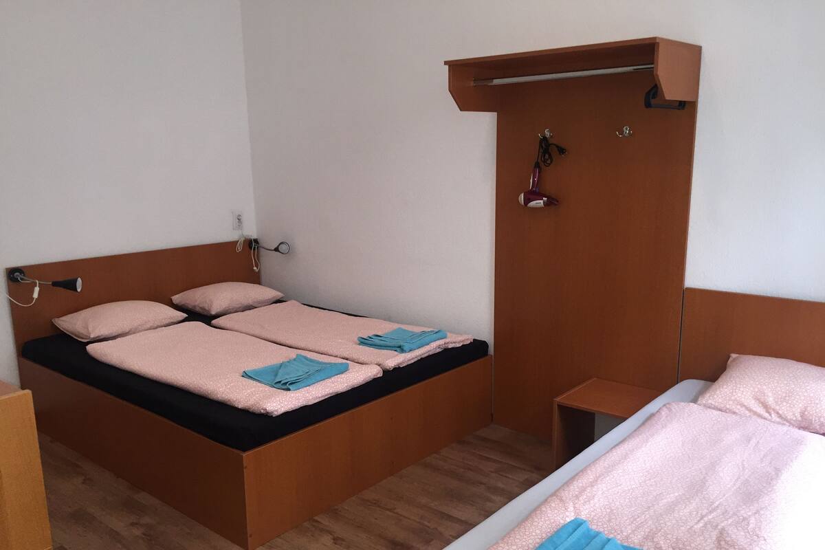 Une chambre avec un lit simple, une tête de lit en bois, une table de chevet et une armoire.