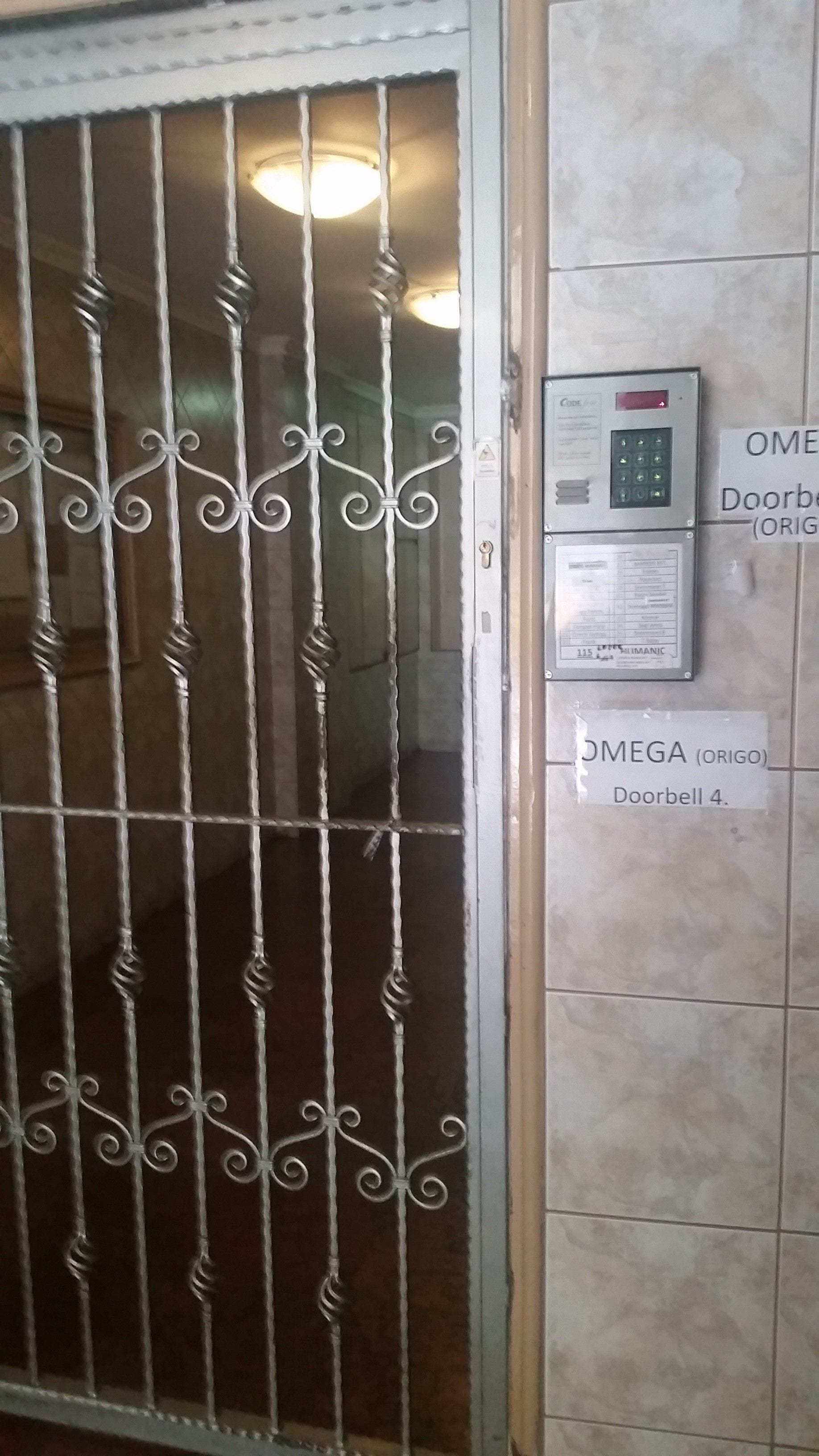 Una porta amb un teclat de seguretat i un senyal que indica "OMEGA (ORIGO) Timbre 4".