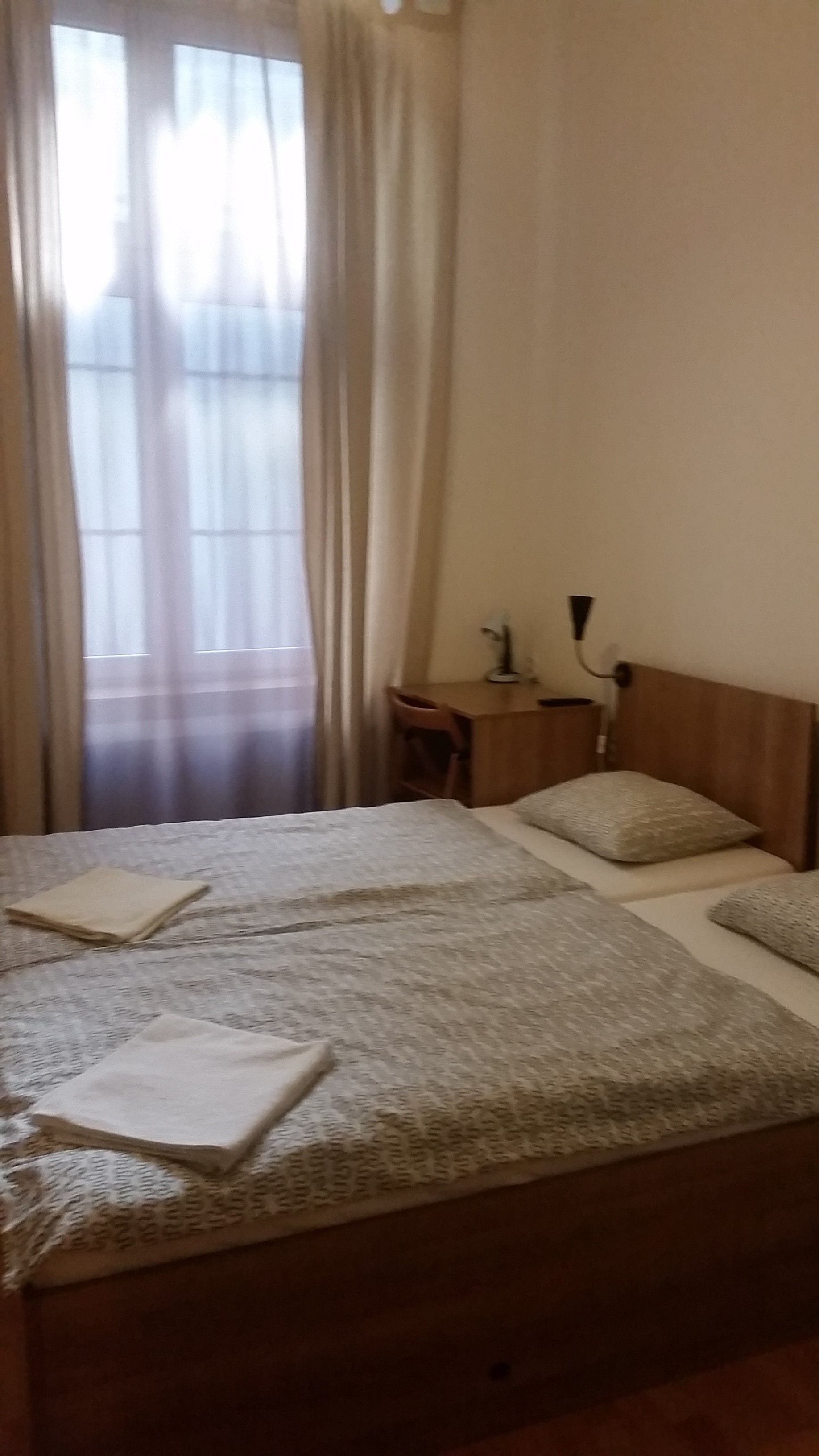 Une chambre d’hôtel avec deux lits, un bureau, une chaise et une lampe.