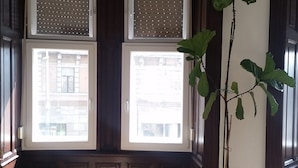 A room with a large window, a potted plant, and a decorative bench.