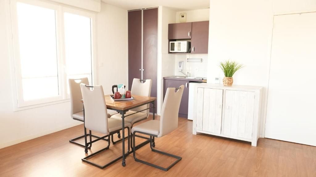 Un espacio habitable compacto con comedor, kitchenette y un mueble pequeño.