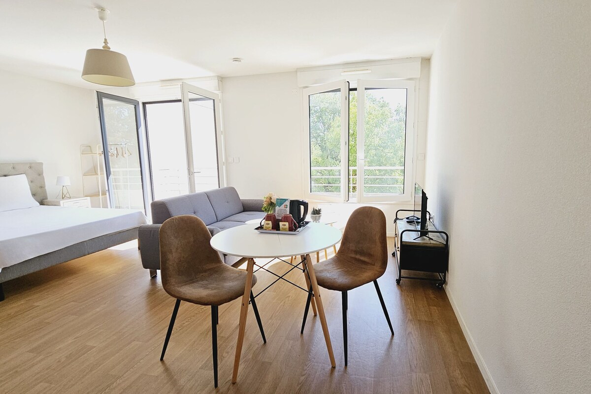 Una habitación moderna y luminosa con una cama, un sofá, una mesa de comedor con sillas y un mueble para la televisión.