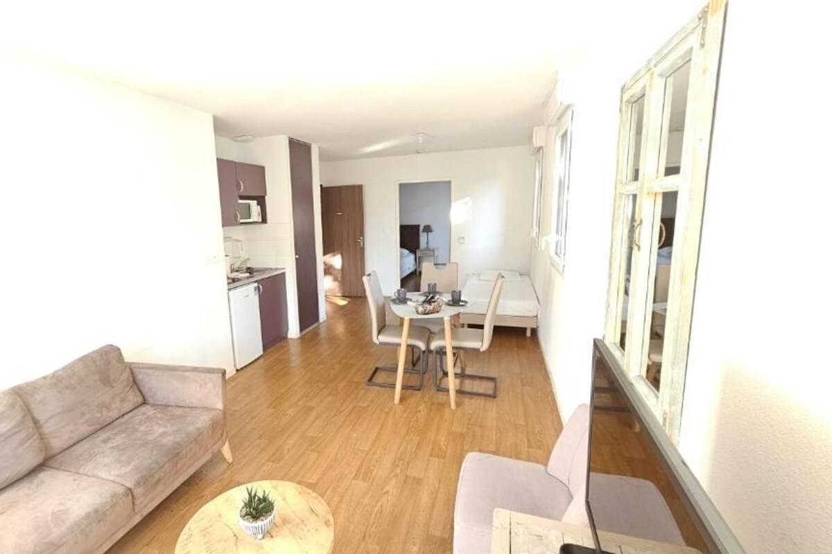 Una sala de estar moderna con un sofá, una mesa de centro y un comedor con mesa y sillas.