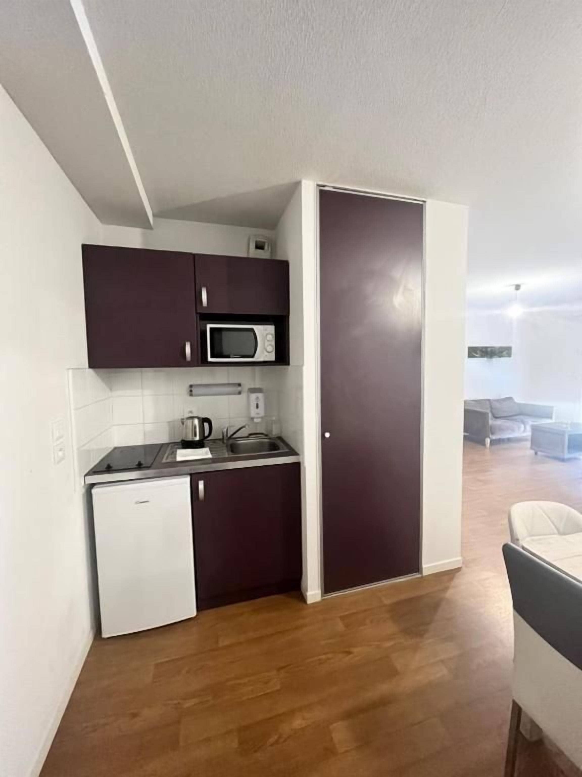 A compact kitchen with a microwave, a small refrigerator, and a sink.