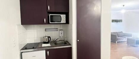 A compact kitchen with a microwave, a small refrigerator, and a sink.