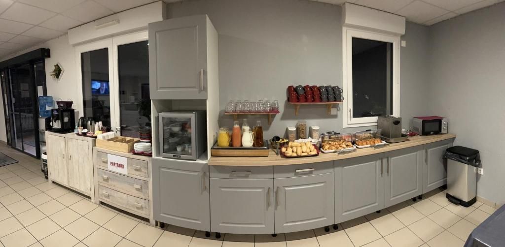 Een keukenhoek met een inbouwmagnetron, koffieapparaat en diverse etenswaren op het aanrecht.
