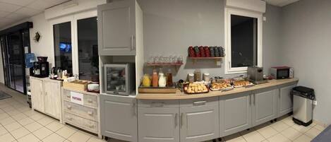 A kitchen area with a built-in microwave, coffee machine, and various food items on the counter.