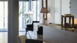 Una zona de recepción moderna con un mostrador de madera, un sofá negro y una lámpara.