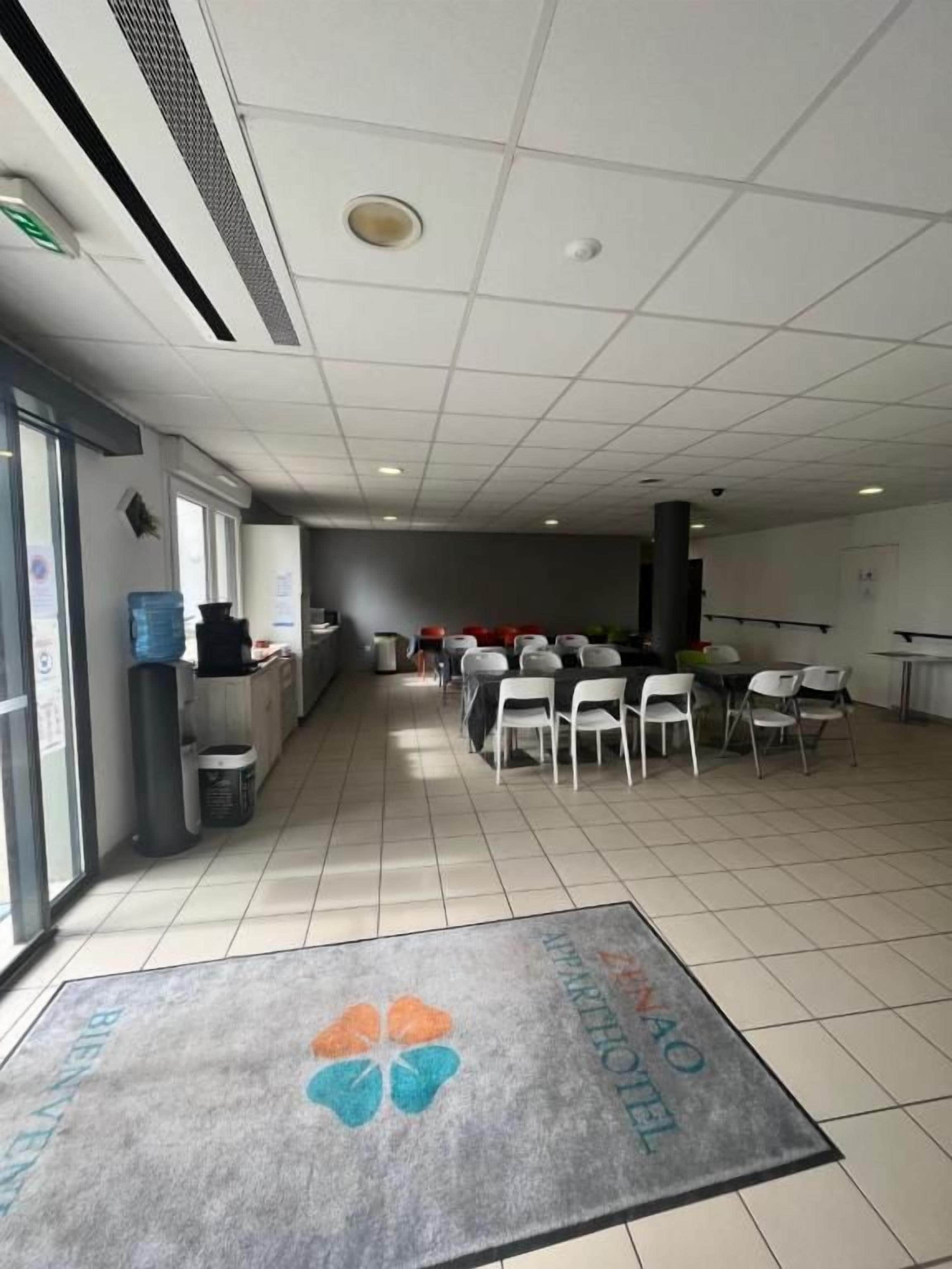 A spacious room with a tiled floor, a reception desk, and several chairs arranged for seating.
