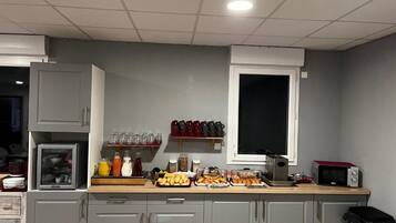 Una cucina con mobili grigi, un forno a microonde e diversi prodotti alimentari sul bancone.