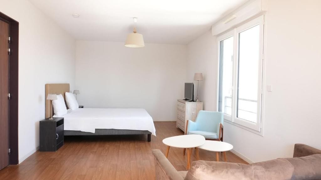 A bedroom with a bed, bedside tables, a chair, a desk, and a window.
