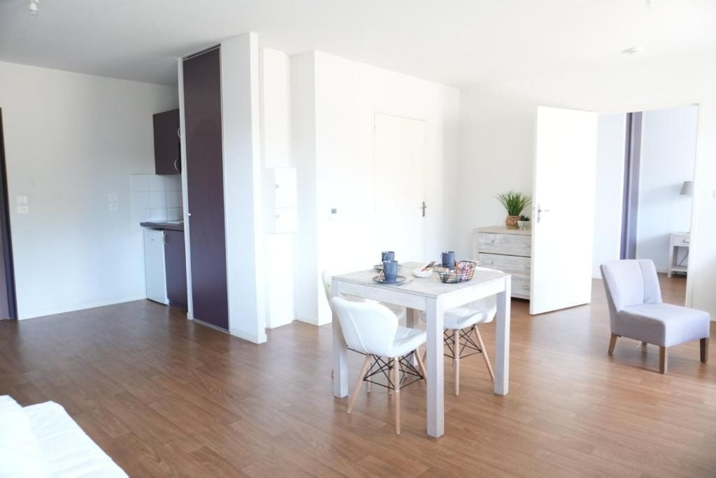 Una habitación moderna, bien iluminada, con una mesa de comedor, sillas y una pequeña cocina.