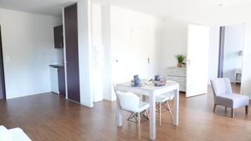 Una habitación moderna, bien iluminada, con una mesa de comedor, sillas y una pequeña cocina.