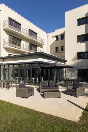 Relax in a spacious outdoor patio area with wicker sofas and a dining table.