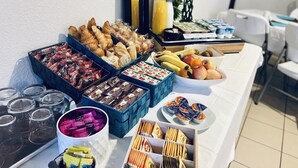 Una mesa de buffet con diversas opciones de comida, incluyendo pasteles, frutas y bebidas.