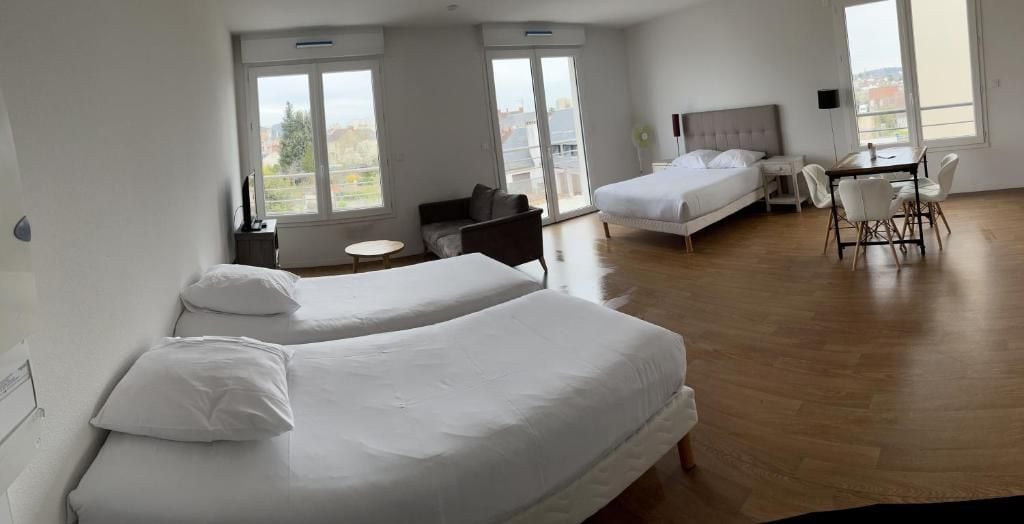 Une chambre d’hôtel avec deux lits, une table à manger avec des chaises, une petite table ronde et une vue par la fenêtre.