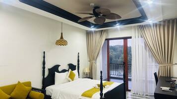 A hotel room with a bed, a sofa, a desk, and a balcony with curtains.