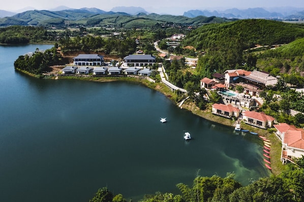 A lakeside property with multiple buildings, a dock with boats, and a view of the surrounding hills.