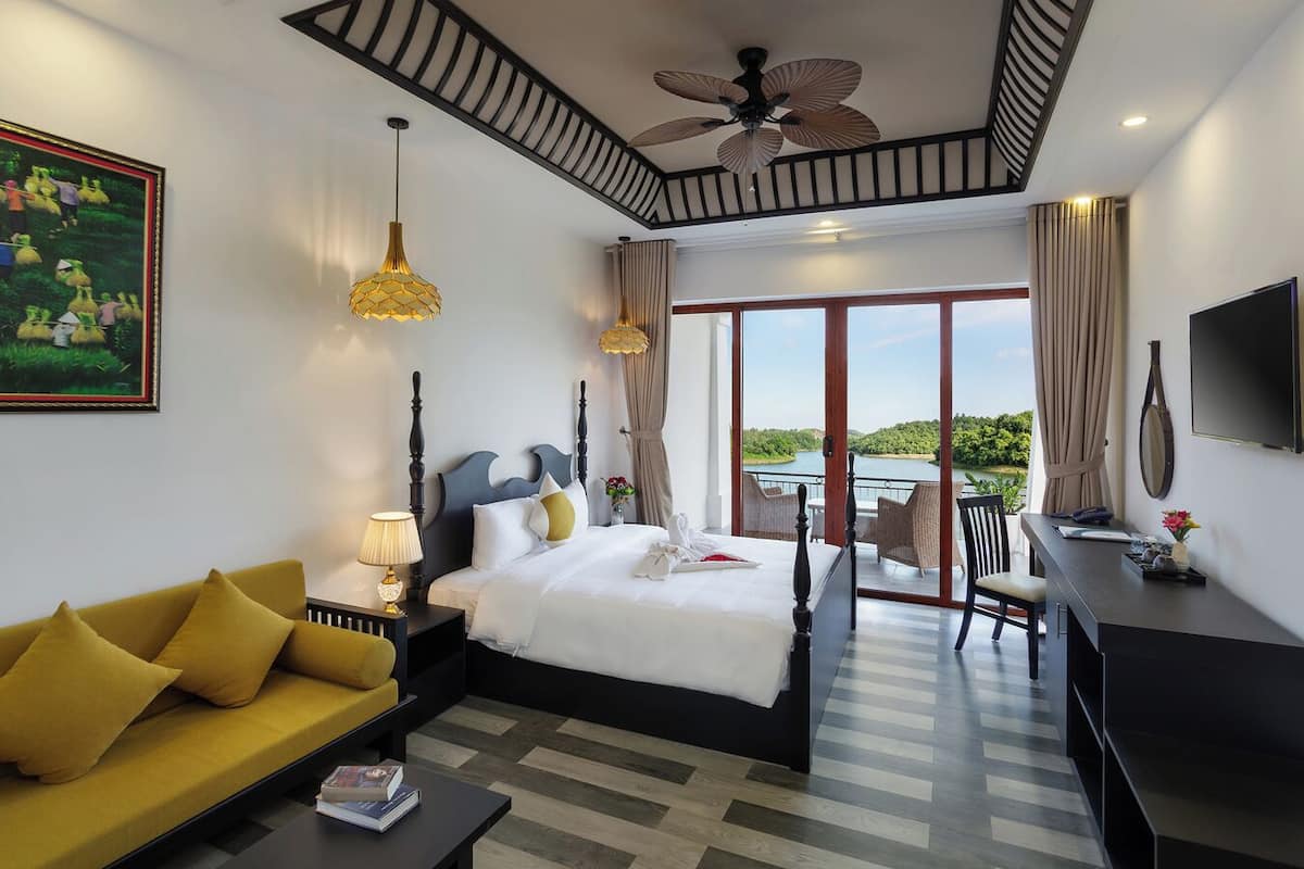 Een moderne hotelkamer met een groot bed, een bank, een bureau en een balkon met uitzicht.