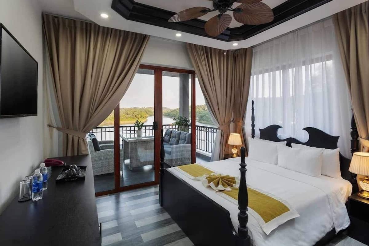 Hotelkamer met een bed, een televisie, een balkon met uitzicht en een plafondventilator.