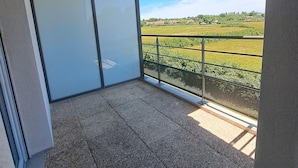 Un balcón con vista a un campo verde y casas.
