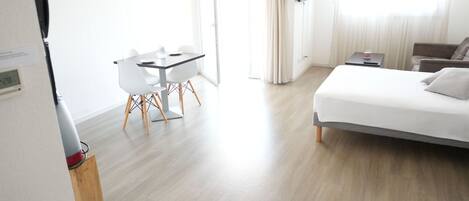 A modern hotel room with a bed, a desk, and a chair.