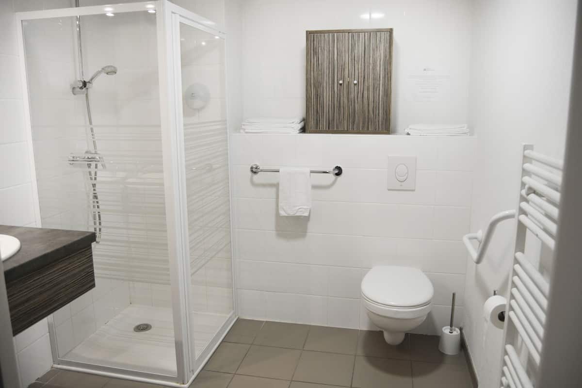 Un baño moderno con ducha de vidrio, inodoro y toallero.
