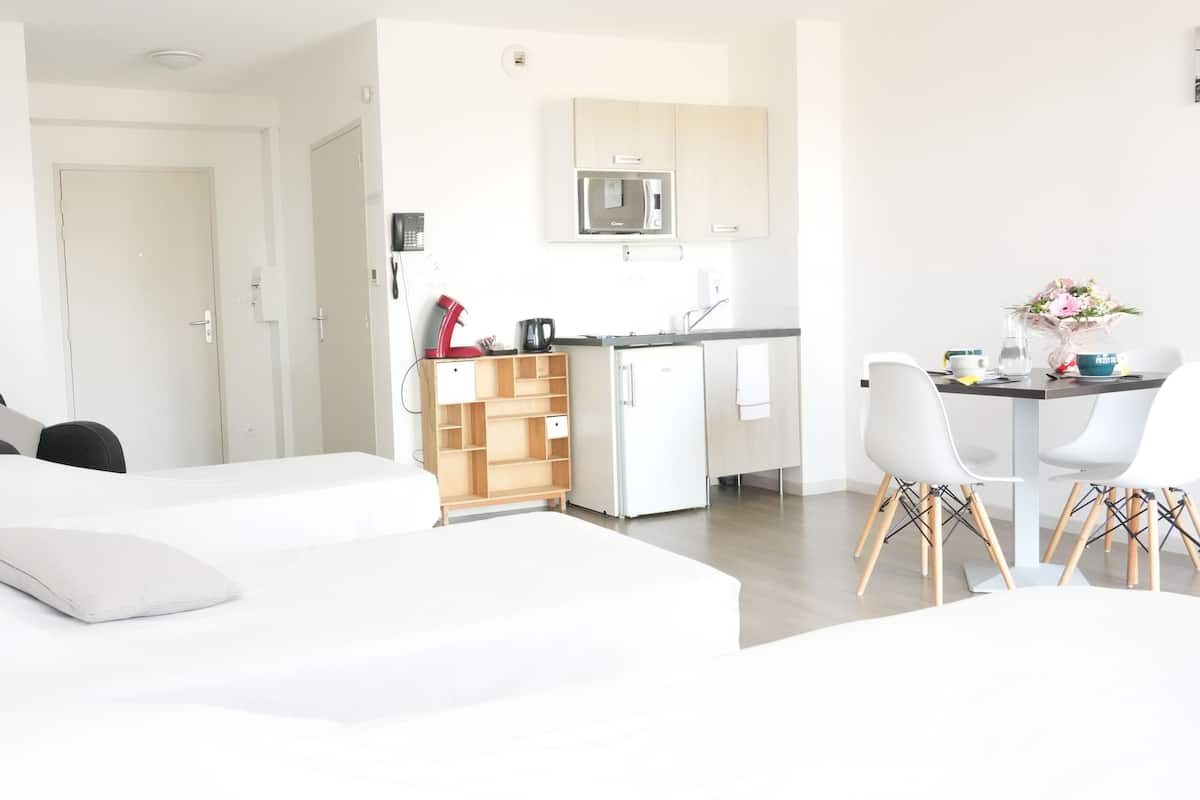 Una habitación de hotel moderna con dos camas, un kitchenette y un comedor.