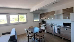 Una cocina moderna con armarios de madera, una mesa de comedor con sillas y un horno empotrado.