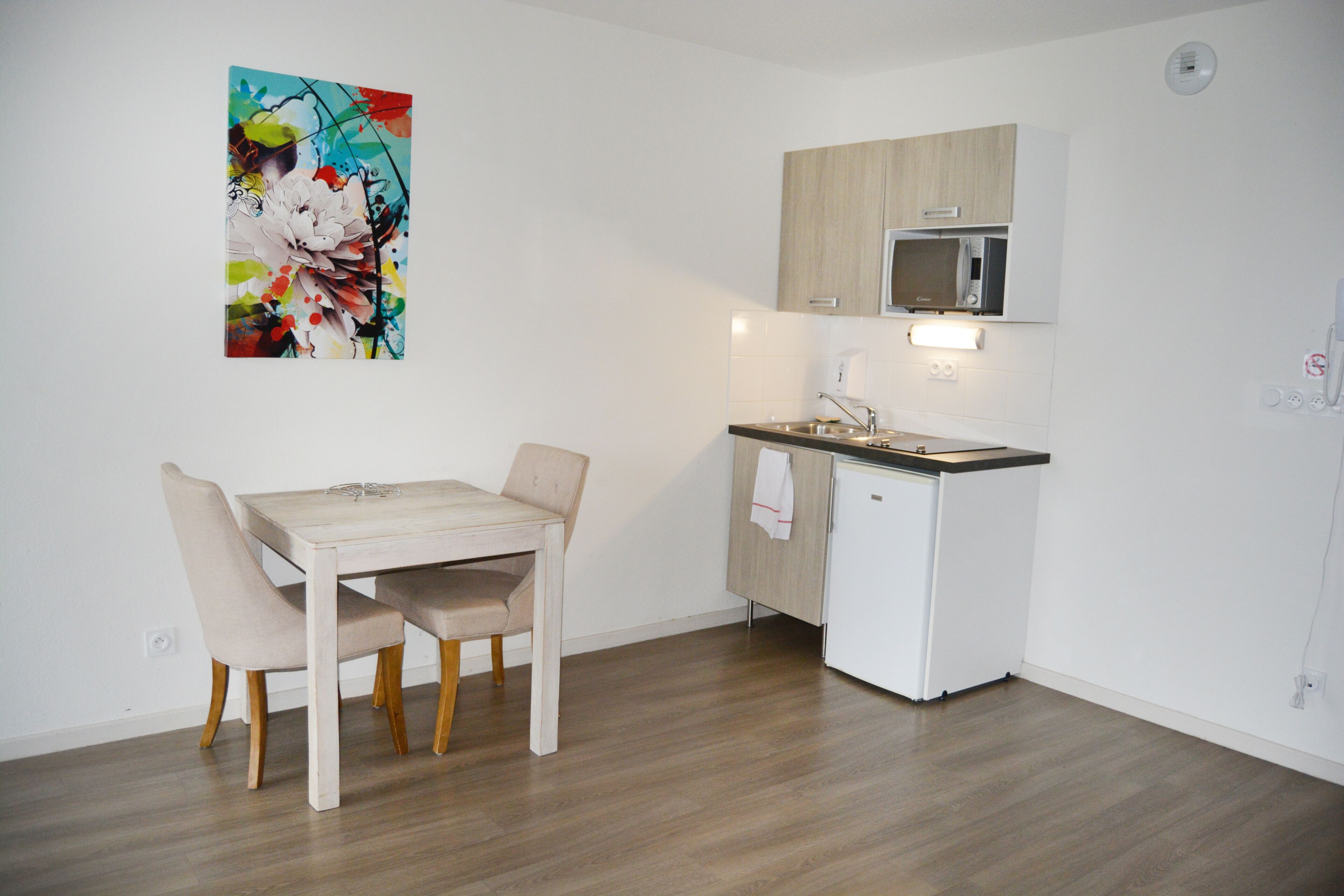 Une cuisine compacte comprenant une table et des chaises, un four à micro-ondes et un petit réfrigérateur.