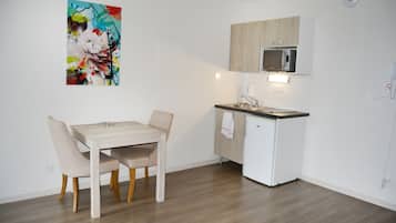Une cuisine compacte comprenant une table et des chaises, un four à micro-ondes et un petit réfrigérateur.