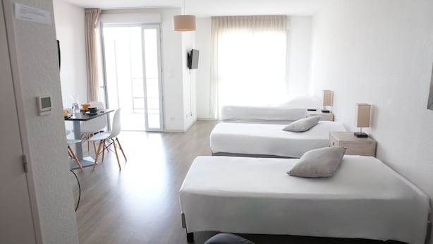Habitación de hotel con dos camas, un escritorio y una silla.
