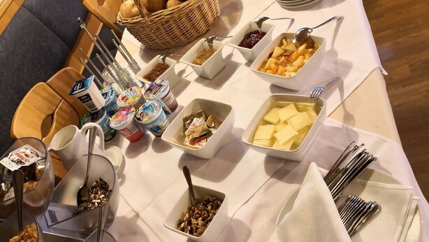 Ein reichhaltiges Buffet mit verschiedenen Speisen und Besteck auf einer Tischplatte.