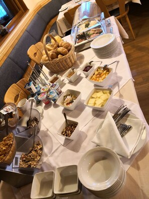 Een buffetopstelling met verschillende gerechten en bestek op een tafel.