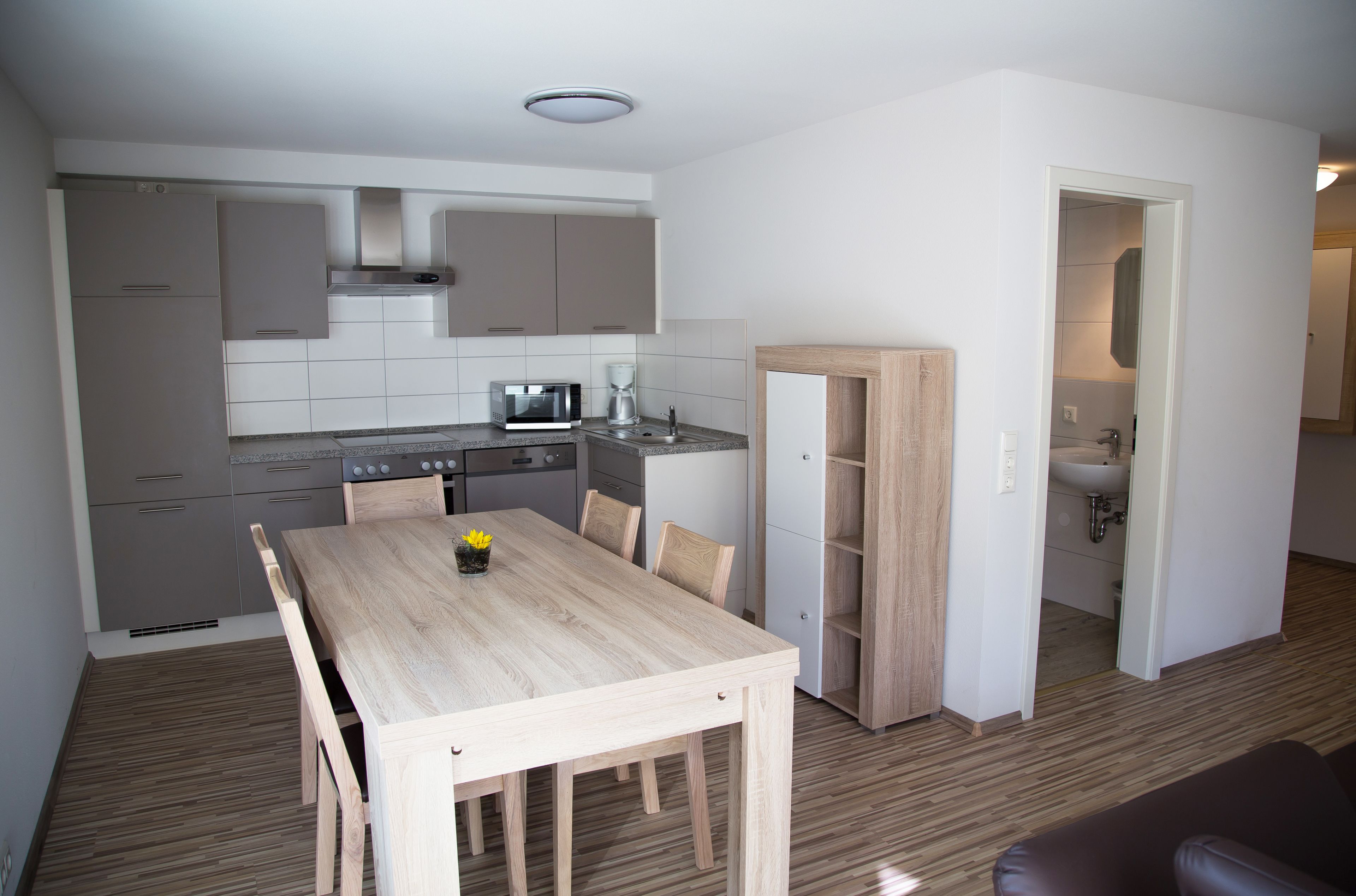 Cocina compacta con electrodomésticos modernos, una mesa de comedor y un baño independiente.