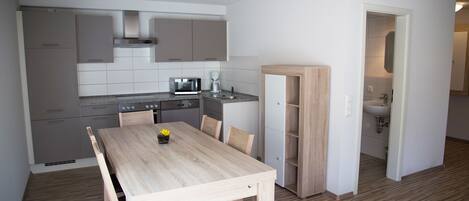 Cocina compacta con electrodomésticos modernos, una mesa de comedor y un baño independiente.