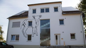 Ein zweistöckiges Gebäude mit einem großen Fenster und einem Wandgemälde eines Kälbchens.