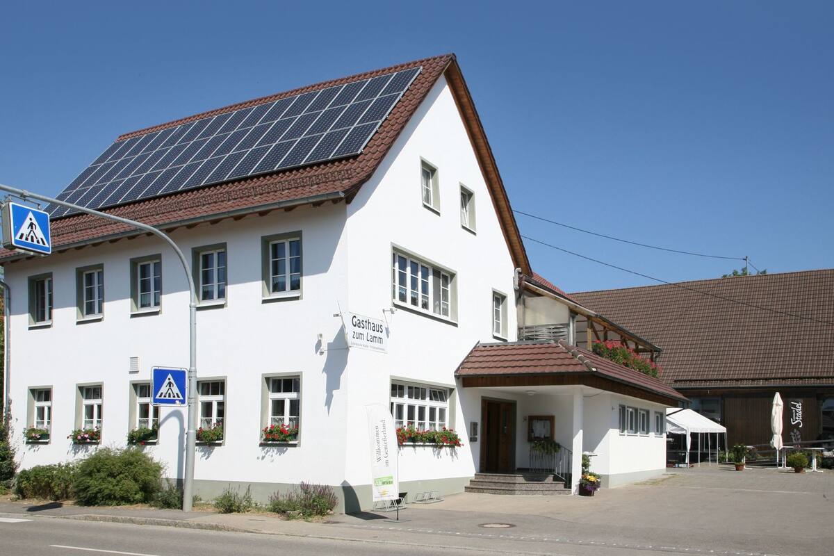 Ein Gebäude mit einem Schild, das „Gasthaus zum Lamm“ zeigt, und einer Solaranlage auf dem Dach.