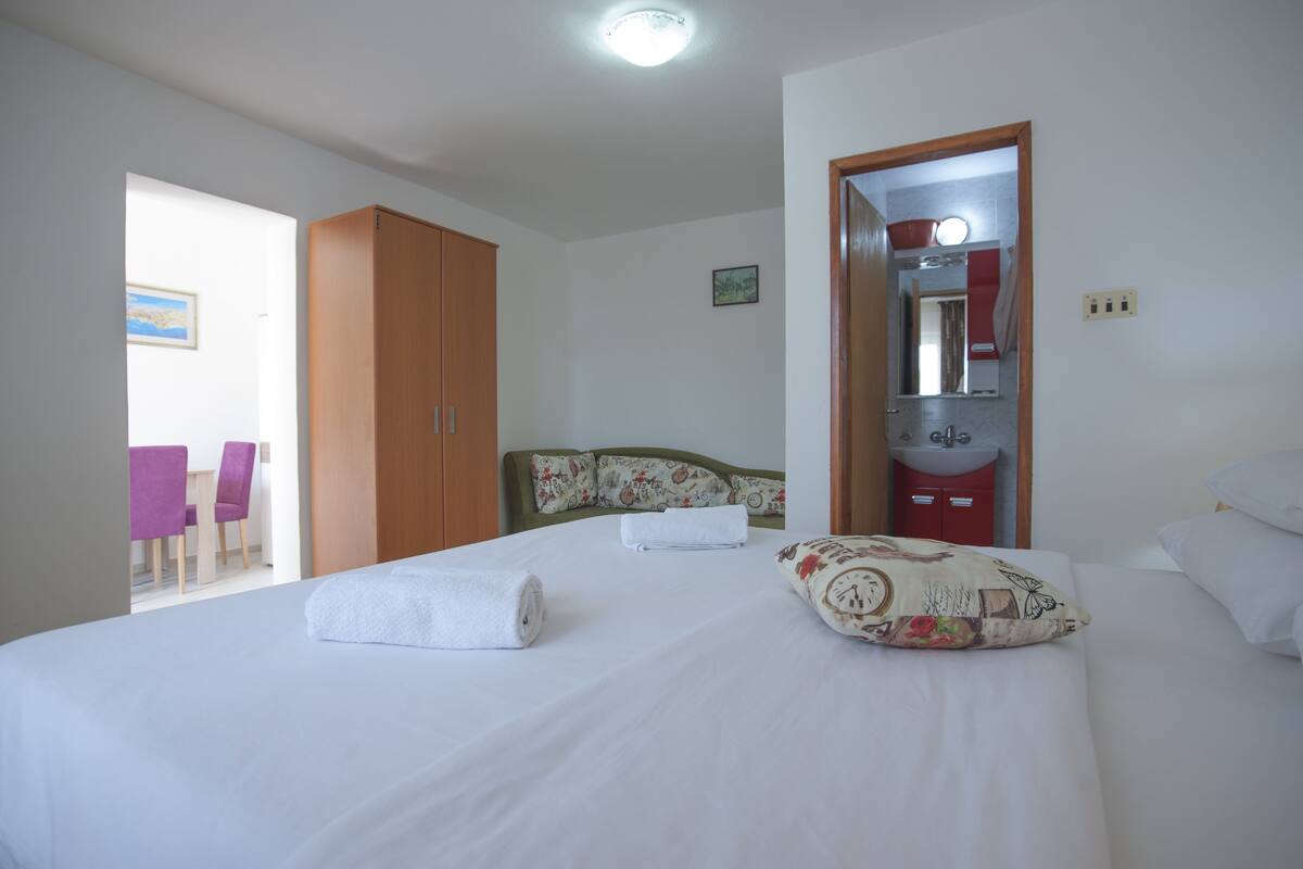 A hotel room with a bed, a bathroom, and a small table with chairs.