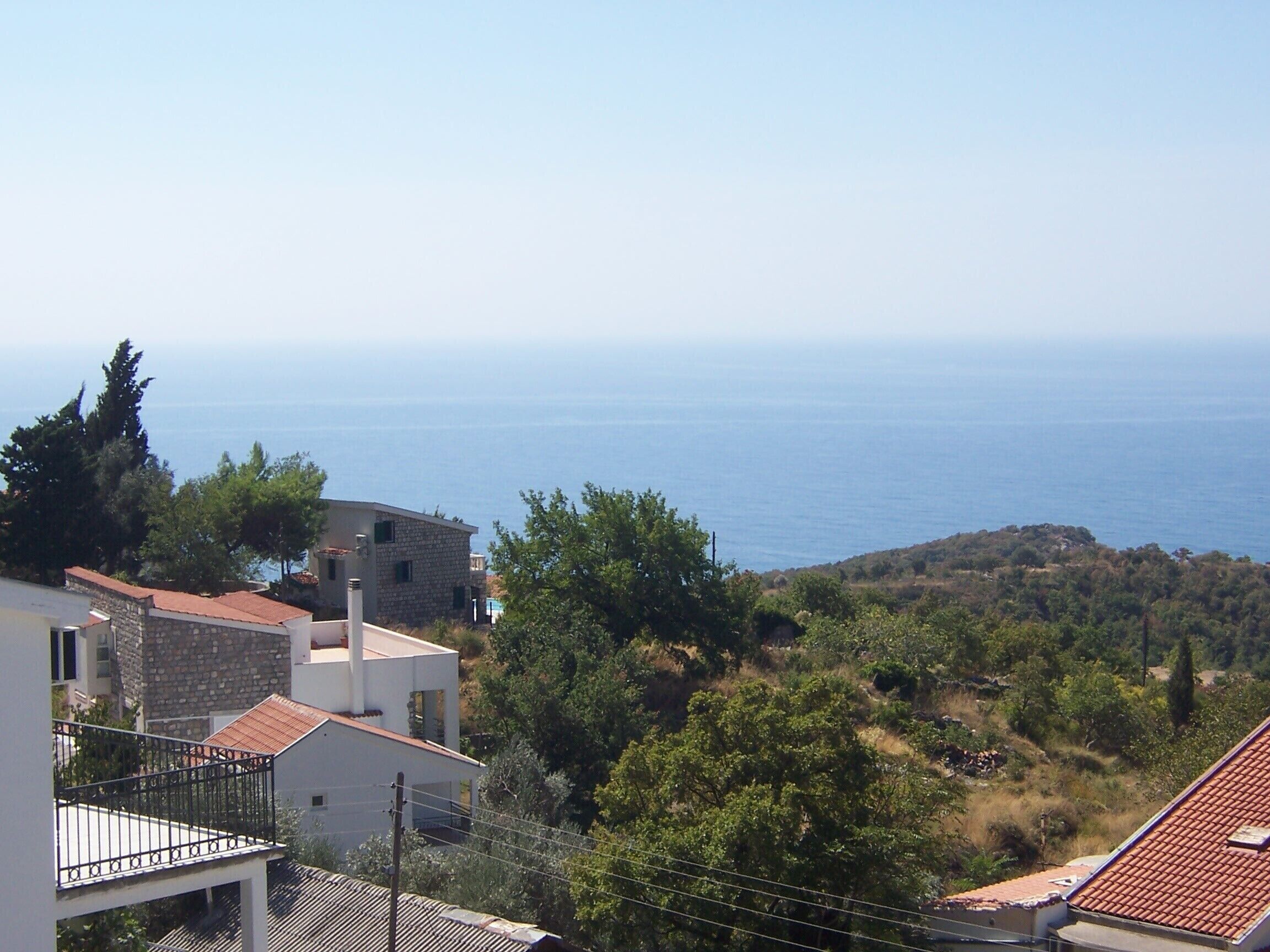 A coastal residential area with stone buildings, a balcony, and a view of the sea.