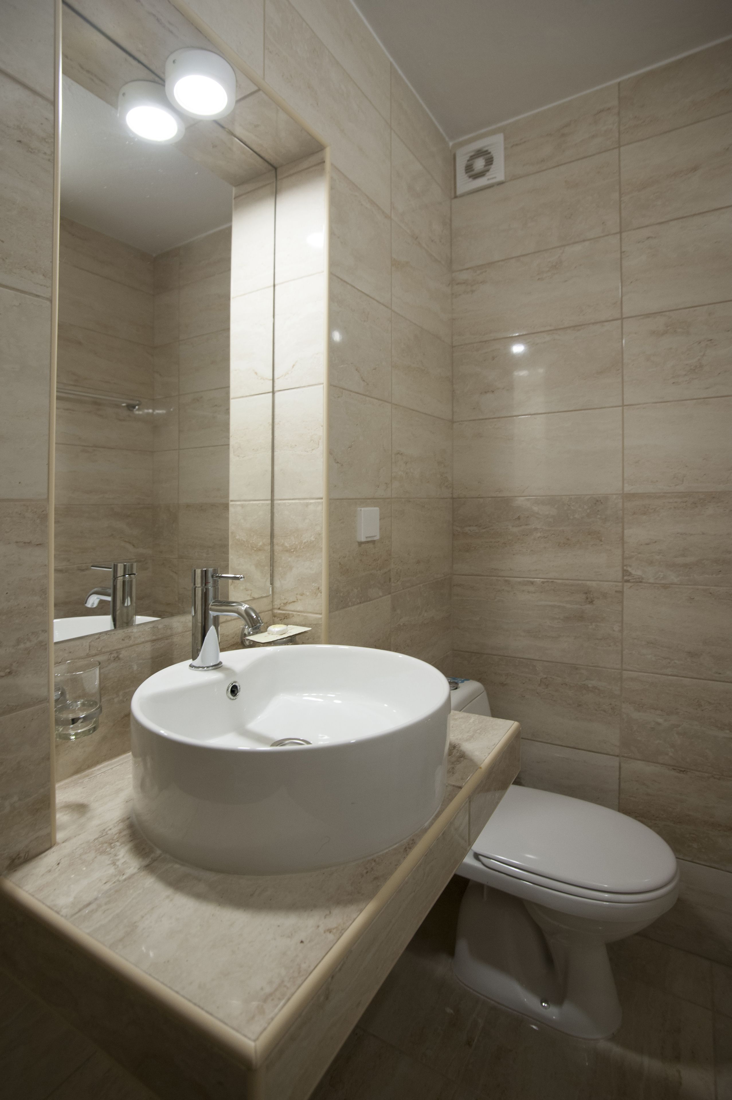 A modern bathroom with a large sink, a toilet, and a mirror.