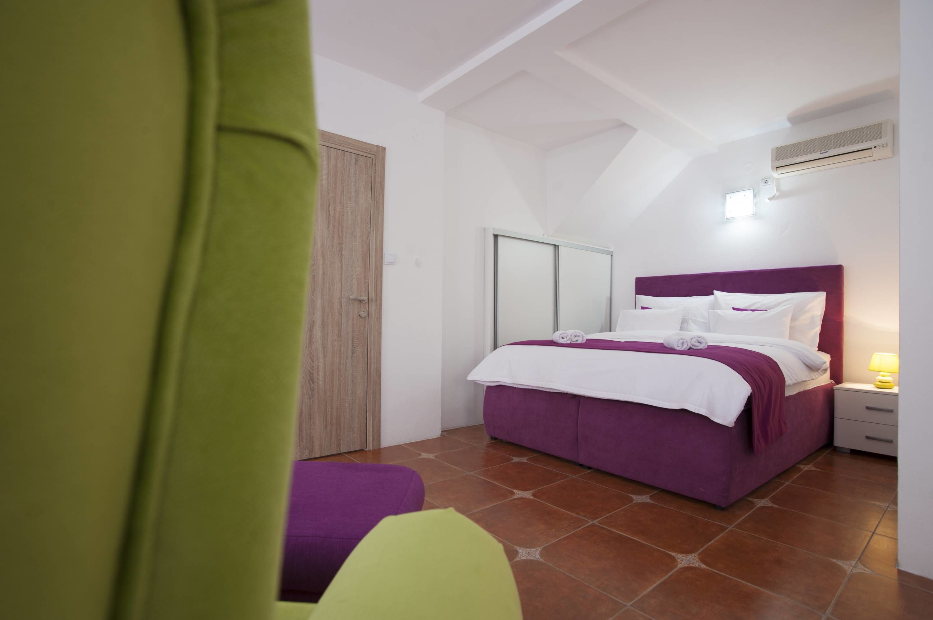 Ein Schlafzimmer mit Bett, Nachttisch, Lampe und Tür.