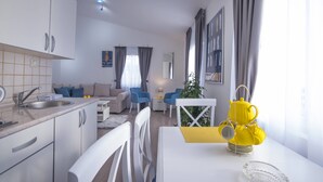 Una cocina moderna con armarios blancos, un lavamanos y un comedor con una mesa y sillas blancas.
