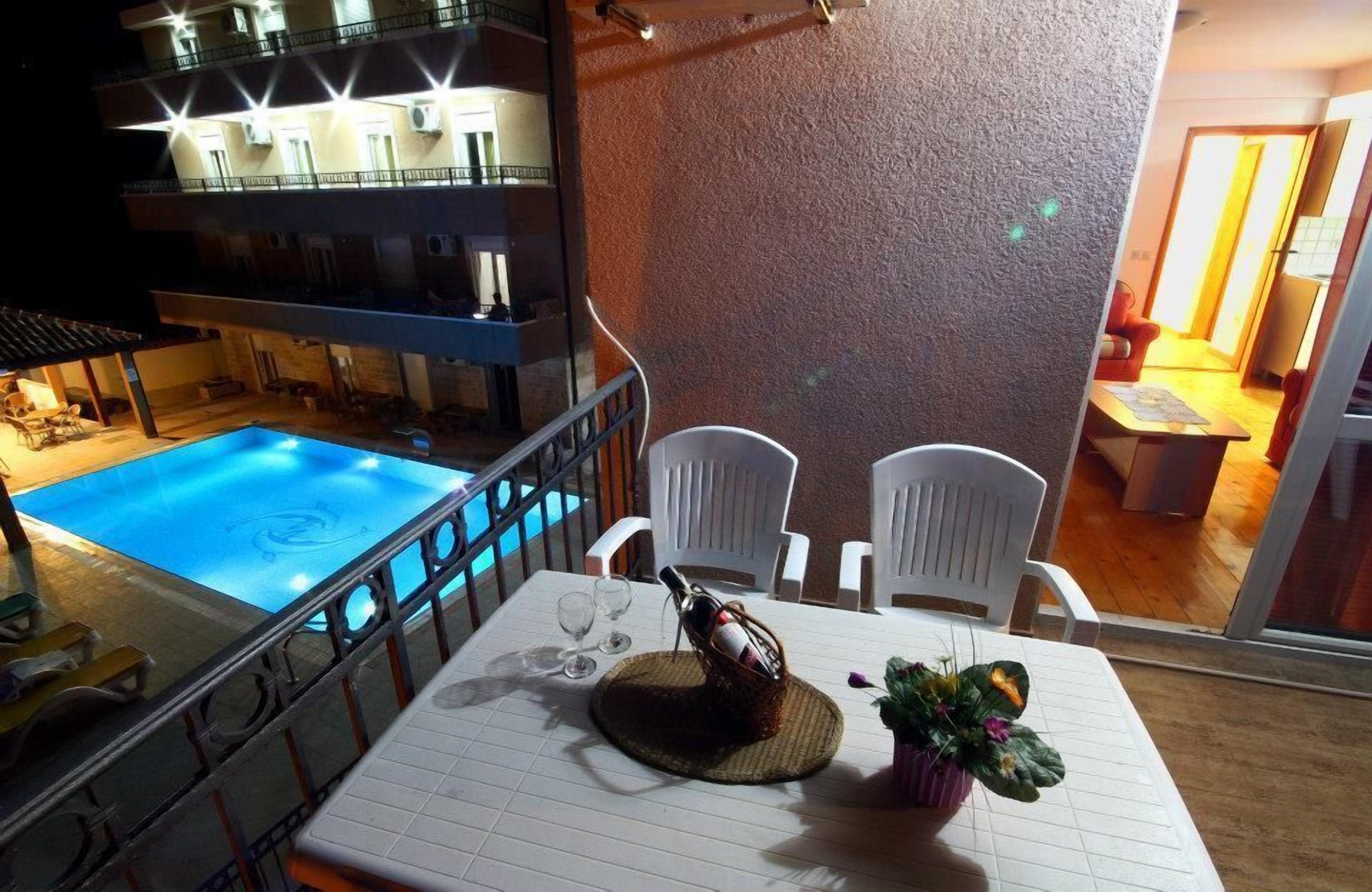 Comedor con una mesa lista para dos personas, con vista a una piscina.